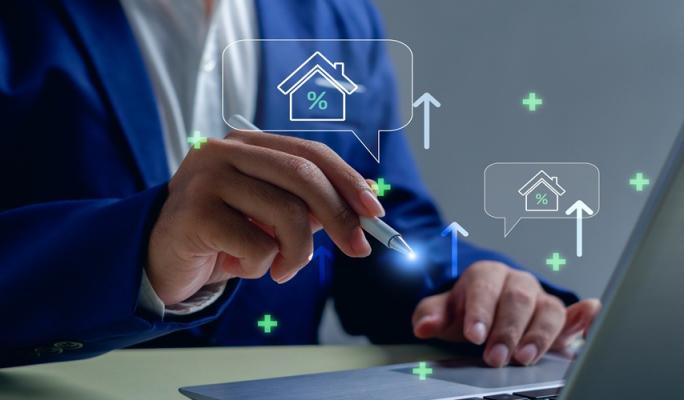 Imagem de uma pessoa usando um laptop com gráficos e ícones de casa, porcentagem e aumento, simbolizando análises imobiliárias e mercado de imóveis.