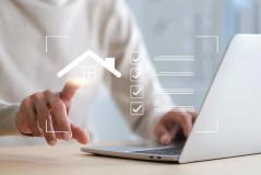 Uma mão toca um ícone brilhante de casa em uma interface digital, ao lado de uma lista de verificação e um notebook.
