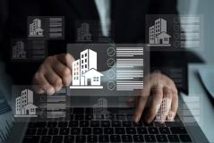  Mãos operam um teclado de notebook com diversos ícones flutuantes de prédios e listas de verificação digital.