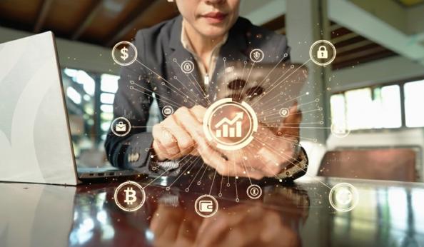 Imagem de uma mulher usando um smartphone, com gráficos de crescimento financeiro, destaque para ícones de moedas digitais e segurança, simbolizando inovação financeira e tecnologia de investimentos.