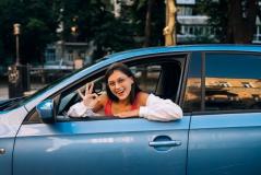  Uma jovem sorridente de óculos faz um sinal de 