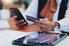  Uma pessoa segura um cartão de crédito e um smartphone, realizando uma transação digital ou pagamento online.