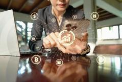  Uma pessoa usa um smartphone com gráficos de crescimento financeiro, criptomoedas e segurança digital projetados ao redor.